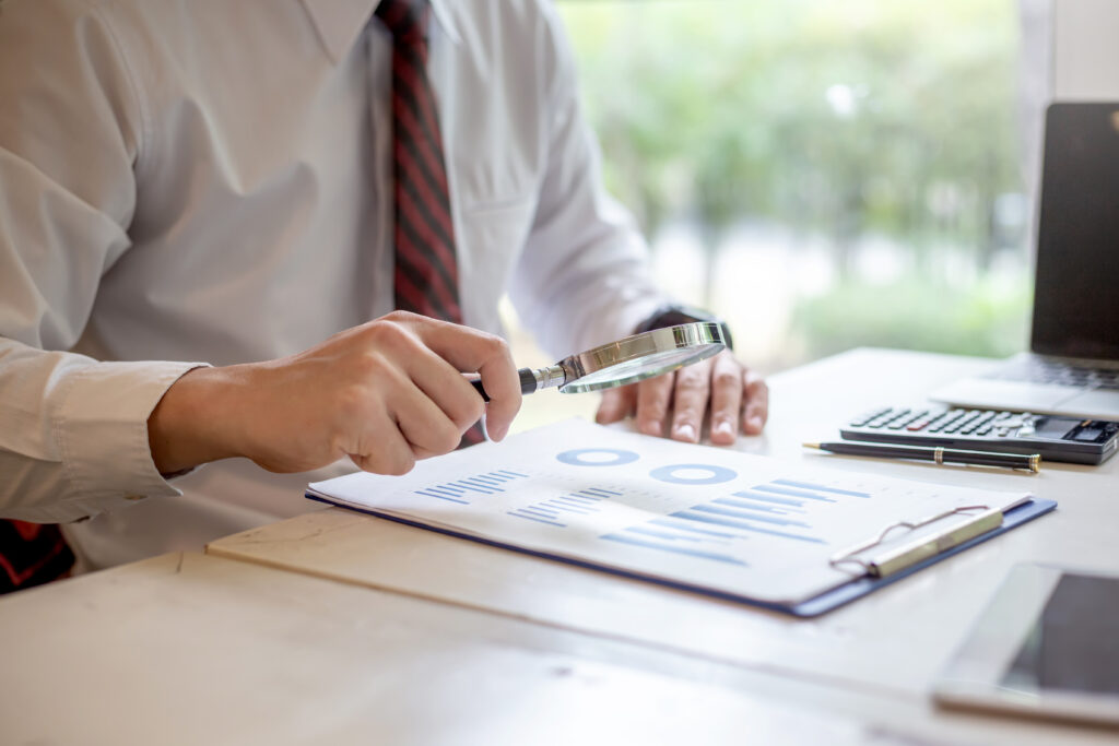 man examining paper with magnifying glass