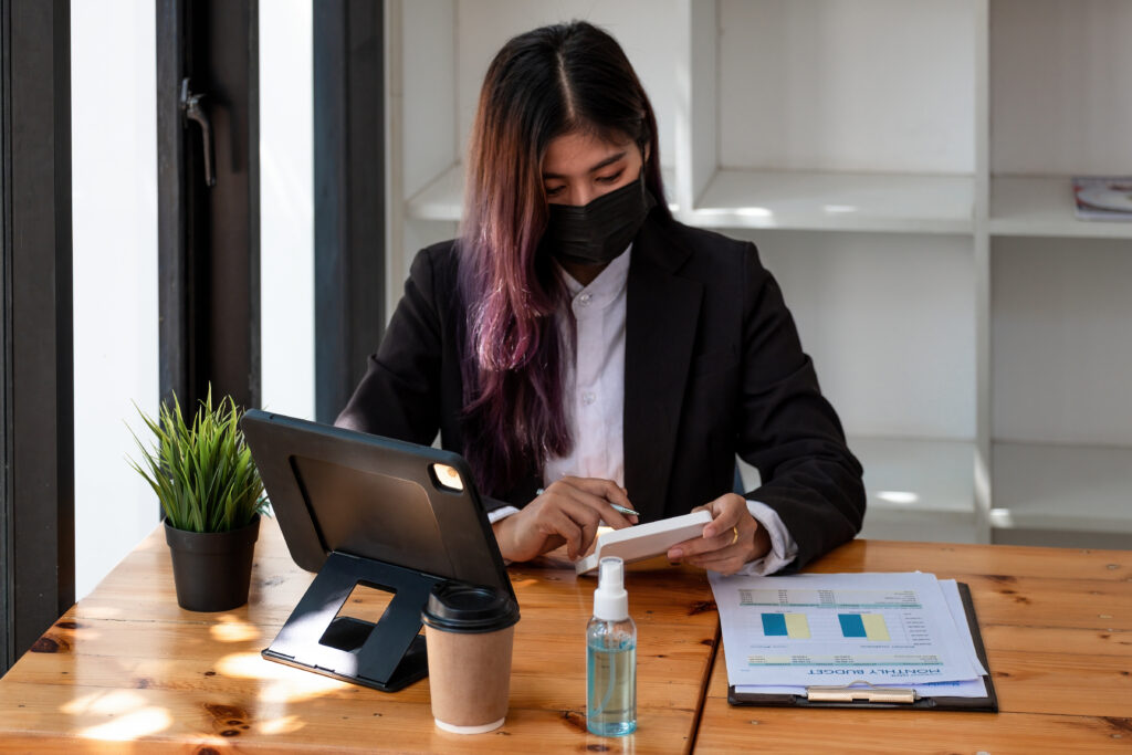 woman in a mask using a calculator 