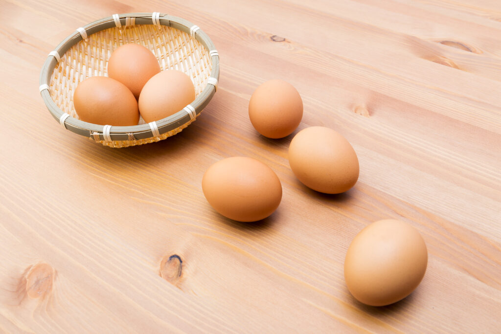 basket of eggs with 4 eggs strewn on the table