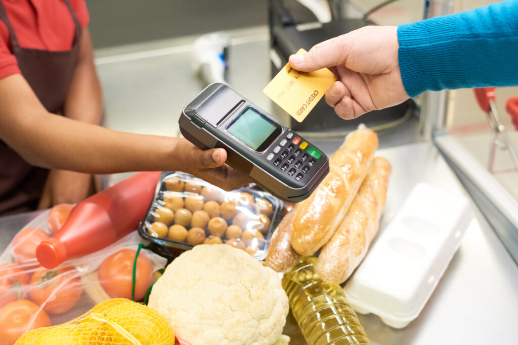 man buying groceries with credit card tap