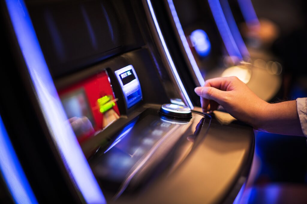 Casino Slot Machine Games Playing. Woman Hand on the Machine Bet Button. Closeup Photo