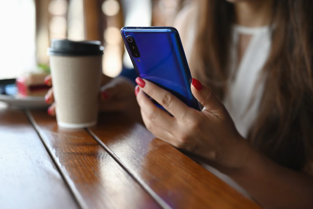 woman having coffee and reading on her phone