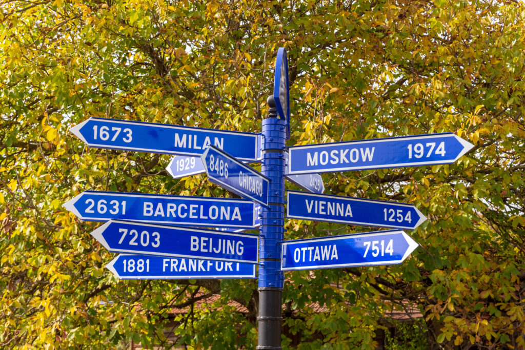 road sign showing distance to dfifferent cities across the globe