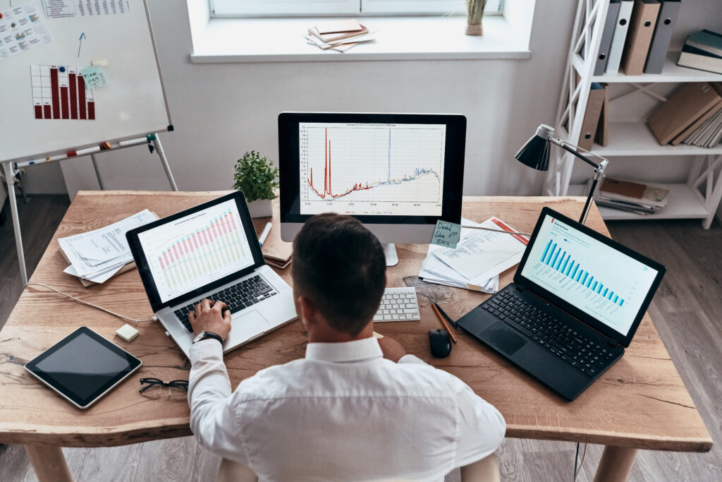 man checking stocks on 3 devices