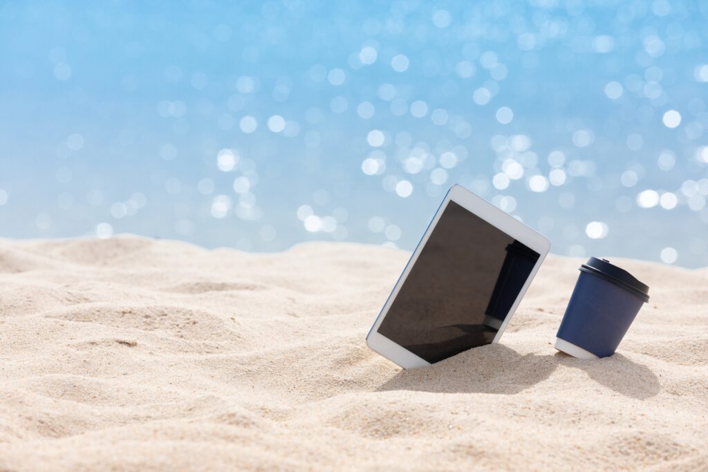 ipad and coffee cup on the beach