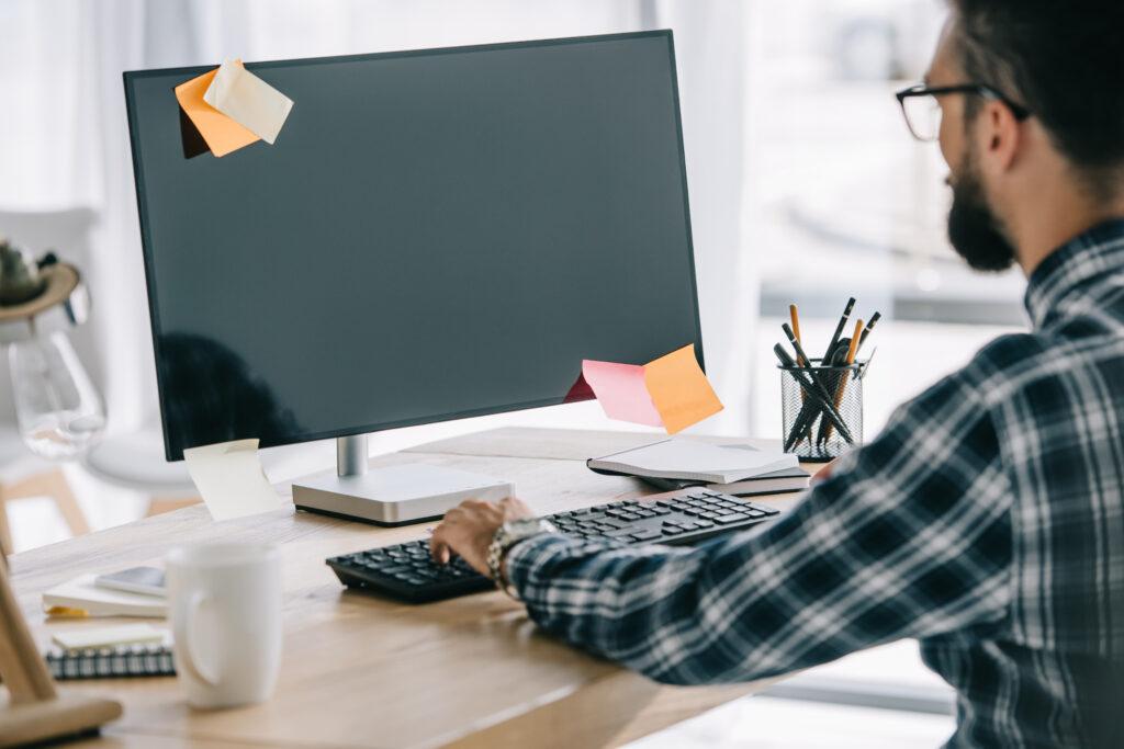 man staring at blank monitor with sticky notes on it